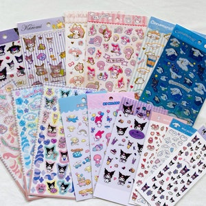 May include: A collection of colorful sticker sheets featuring popular Japanese cartoon characters, including My Melody, Cinnamoroll, and Kuromi. The stickers feature various designs, including hearts, stars, clouds, and the characters themselves.