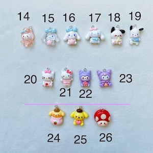 May include: A collection of 26 colourful charm pendants featuring various cartoon characters, including Hello Kitty, My Melody, and Pompompurin. The charms are made of polymer clay and have a variety of colours and designs.