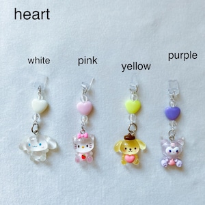 May include: Four heart-shaped charms with different characters on them. The charms are white, pink, yellow, and purple. Each charm has a small heart bead and a clear bead above it. The characters are a white dog, a pink cat, a yellow dog, and a purple cat.