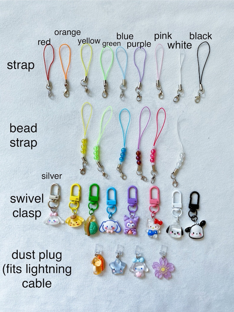 Pode incluir: Conjunto de pingentes de telefone coloridos com diferentes designs. Os pingentes incluem uma variedade de cores, como vermelho, laranja, amarelo, verde, azul, roxo, rosa, branco e preto. Os pingentes s&atilde;o feitos de diferentes materiais, incluindo contas, metal e pl&aacute;stico. Os pingentes s&atilde;o presos a uma variedade de tiras, incluindo tiras com contas, tiras lisas e tiras com um fecho girat&oacute;rio. Os pingentes tamb&eacute;m est&atilde;o dispon&iacute;veis com uma tampa anti-poeira que se ajusta a um cabo Lightning.