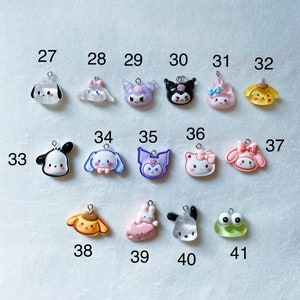May include: A collection of 11 colourful charm pendants featuring cartoon characters such as Hello Kitty, My Melody, and Kuromi. The charms are made of resin and have a glossy finish.