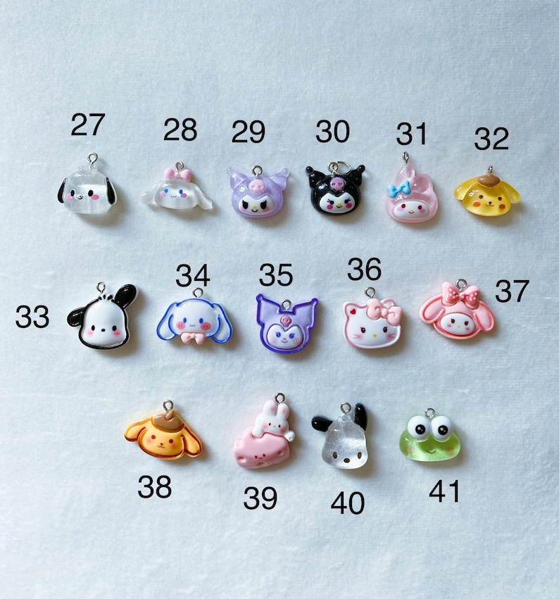 May include: A collection of 11 colourful charm pendants featuring cartoon characters such as Hello Kitty, My Melody, and Kuromi. The charms are made of resin and have a glossy finish.