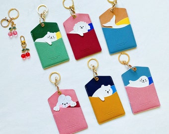 May include: Seven colorful keychains with different animal designs. Each keychain has a small pocket for holding cards or cash. The keychains are made of leather and have gold-colored metal rings.