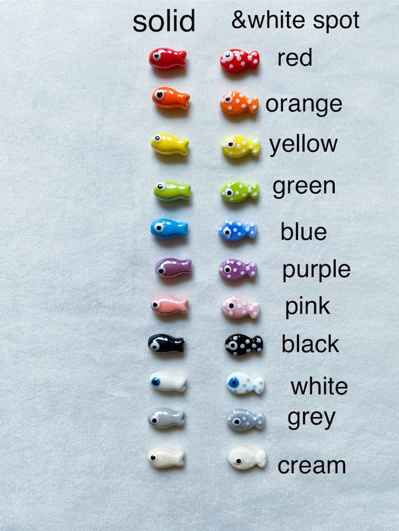 May include: Two rows of ceramic fish charms, one row with solid colors and the other with white spots. The colors are red, orange, yellow, green, blue, purple, pink, black, white, gray, and cream.