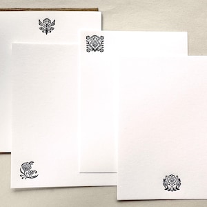 May include: A set of white stationery cards and a brown envelope. Each card features a distinct black ink floral motif printed in different positions, including a centered top design, a top-left corner design, and a bottom-centered design.