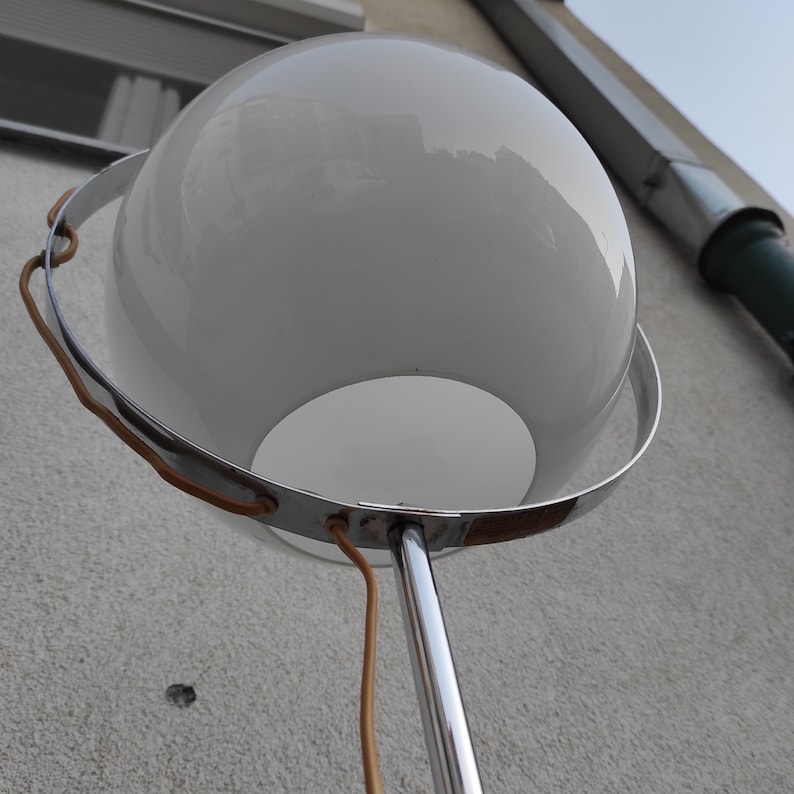 May include: A white globe lamp with a chrome base and a brown cord. The globe is surrounded by a chrome ring.