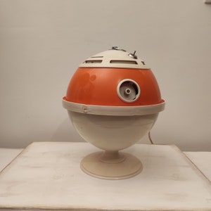 May include: A vintage orange and white plastic table lamp with a round base and a spherical shade. The lamp has a small hole on the side of the shade.