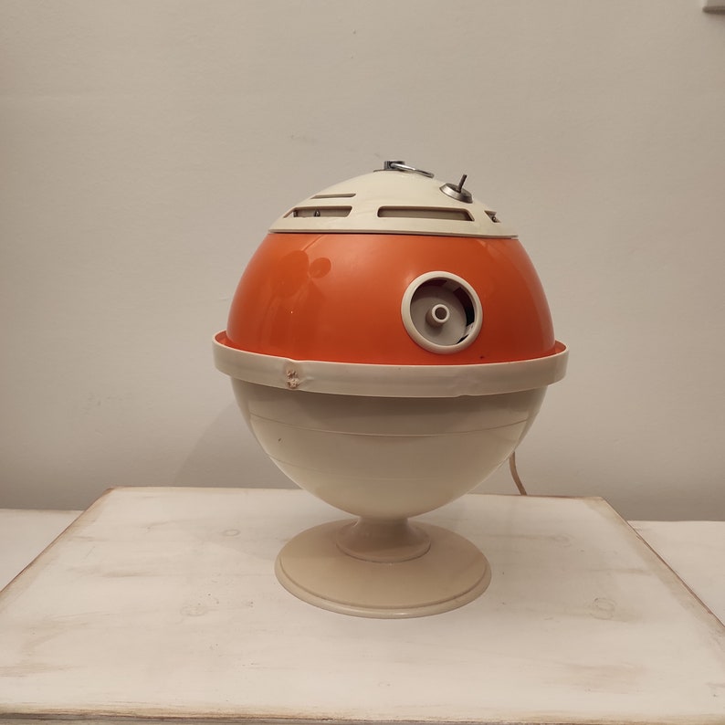 May include: A vintage orange and white plastic table lamp with a round base and a spherical shade. The lamp has a small hole on the side of the shade.