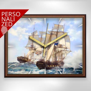 Könnte beinhalten: Rechteckige Wanduhr mit braunem Holzrahmen, die ein Gemälde von Segelschiffen auf See zeigt. Die Uhr hat goldfarbene Zeiger. Das Wort "PERSONALIZED" ist auf einem roten Banner oben links aufgedruckt.