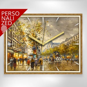 May include: A rectangular wall clock with a gold-colored frame. The clock face features a detailed painting of a European street scene with people, trees, and buildings. The clock hands are gold-colored. The word "PERSONALIZED" is in the upper left corner.