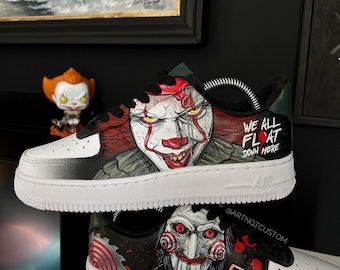 May include: Custom-painted black and white sneakers with a graphic of Pennywise the clown from the movie "IT" on one shoe and a graphic of Billy the Puppet from the movie "Saw" on the other shoe. The Pennywise shoe has the text "We all float down here" on the side. The Billy the Puppet shoe has a cassette tape with the text "Play Me" on it.