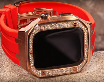 Puede incluir: Un Apple Watch de oro rosa con un bisel engastado con diamantes y una banda de silicona roja brillante.
