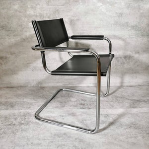 Könnte beinhalten: Ein schwarzer Leder- und Chrom-Cantilever-Stuhl mit gebogener Basis.