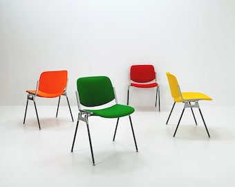 May include: Four chairs with metal frames and colorful fabric seats. The chairs are arranged in a row, with a green chair in the center, a red chair to the right, and two orange chairs to the left.