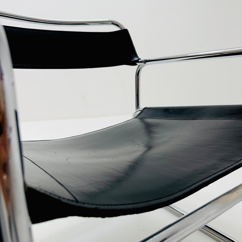 May include: A black leather chair with a chrome frame. The chair is designed in a simple, minimalist style.