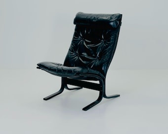 May include: A black leather armchair with a high back and a curved, black wooden frame. The chair has a tufted backrest and seat, and a headrest. The chair is designed for comfort and relaxation.