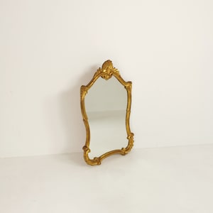 Classic style mirror in gold leaf with shaped frame  Italy 1980s.