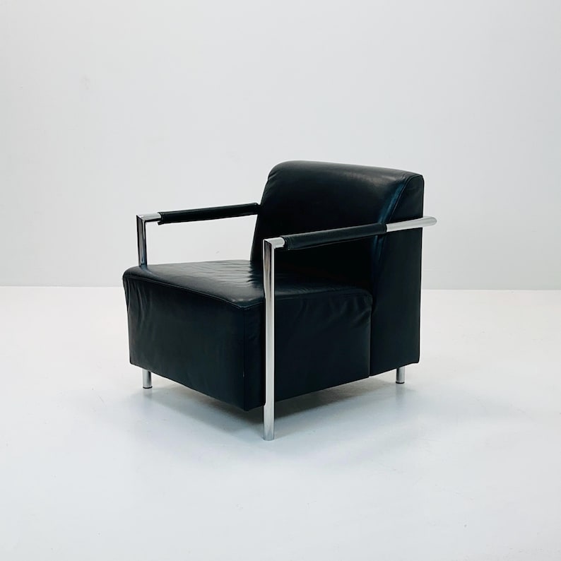 May include: A black leather armchair with chrome legs and arms. The chair has a simple, modern design.