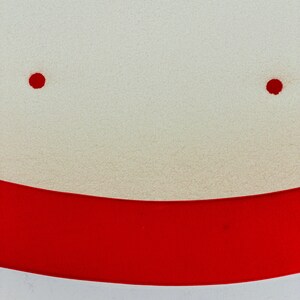 K&ouml;nnte beinhalten: Eine texturierte cremewei&szlig;e Oberfl&auml;che mit einem geschwungenen horizontalen Band in leuchtendem Rot im unteren Bereich. Zwei kleine, kreisf&ouml;rmige, rote Punkte sind symmetrisch im oberen Teil der cremewei&szlig;en Fl&auml;che angeordnet.