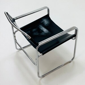 May include: A black leather chair with a chrome frame. The chair has a simple, modern design.