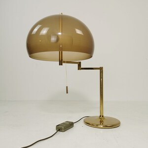 May include: A gold floor lamp with a brown, dome-shaped shade. The lamp has a flexible arm and a pull chain for turning the light on and off.
