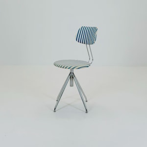 Pode incluir: Cadeira de estilo retro com assento e encosto redondos, ambos estofados em tecido listrado azul e branco. A cadeira tem uma base de tripé cromada e um suporte traseiro de metal curvo.