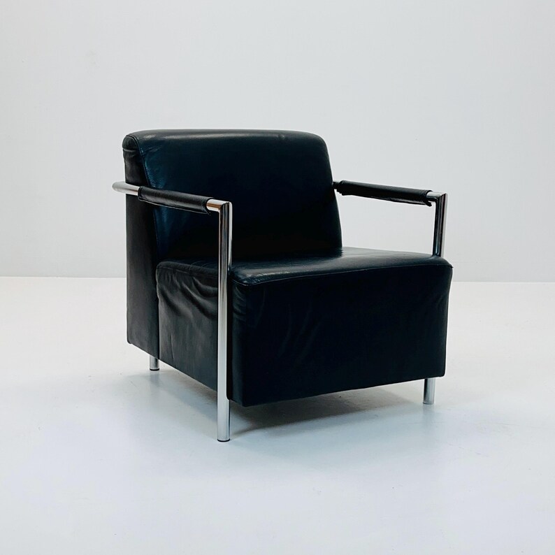 May include: A black leather armchair with chrome legs and arms. The chair has a simple, modern design.
