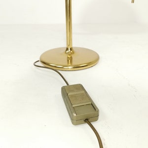May include: A gold floor lamp with a round base and a cord with a foot switch. The lamp has a pull chain for turning the light on and off.
