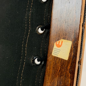 Puede incluir: Primer plano de una silla de madera con tapicer&iacute;a de tela negra. La silla tiene una etiqueta que dice "Westnofa Furniture Made in Norway".