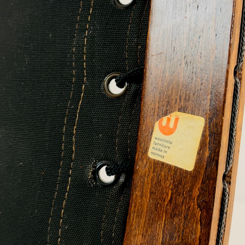 Puede incluir: Primer plano de una silla de madera con tapicer&iacute;a de tela negra. La silla tiene una etiqueta que dice "Westnofa Furniture Made in Norway".