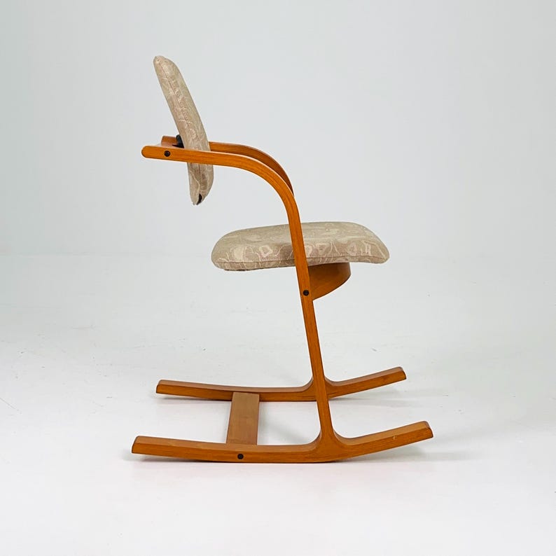Pode incluir: Cadeira de baloi&ccedil;o de madeira com estrutura curva e assento e encosto estampados. A cadeira tem um acabamento castanho claro e um design minimalista, adequado para decora&ccedil;&atilde;o de interiores.