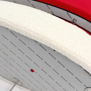 K&ouml;nnte beinhalten: Eine hellgraue Platte mit dem sich wiederholenden schwarzen Schriftzug "DESALTO" auf der Oberfl&auml;che, abgeschlossen mit einer dicken, strukturierten cremewei&szlig;en Kante im Sherpa-Stil. Ein kleiner roter Punkt ist auf der grauen Platte zu sehen.