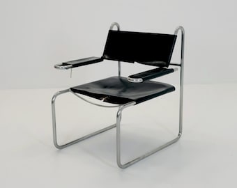 May include: A modern black leather chair with a chrome frame. The chair features a rectangular backrest and seat, with armrests. The frame is made of curved, tubular metal. The chair is designed for seating.