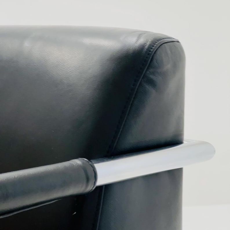 May include: A black leather armchair with a chrome frame. The chair has a curved back and a padded seat.