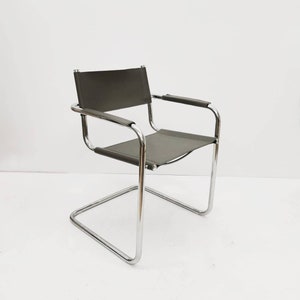 Könnte beinhalten: Ein chromfarbener und grauer Metallstuhl mit schlichtem, modernem Design. Der Stuhl hat eine gebogene Rückenlehne und einen einzigen, durchgehenden Rahmen.