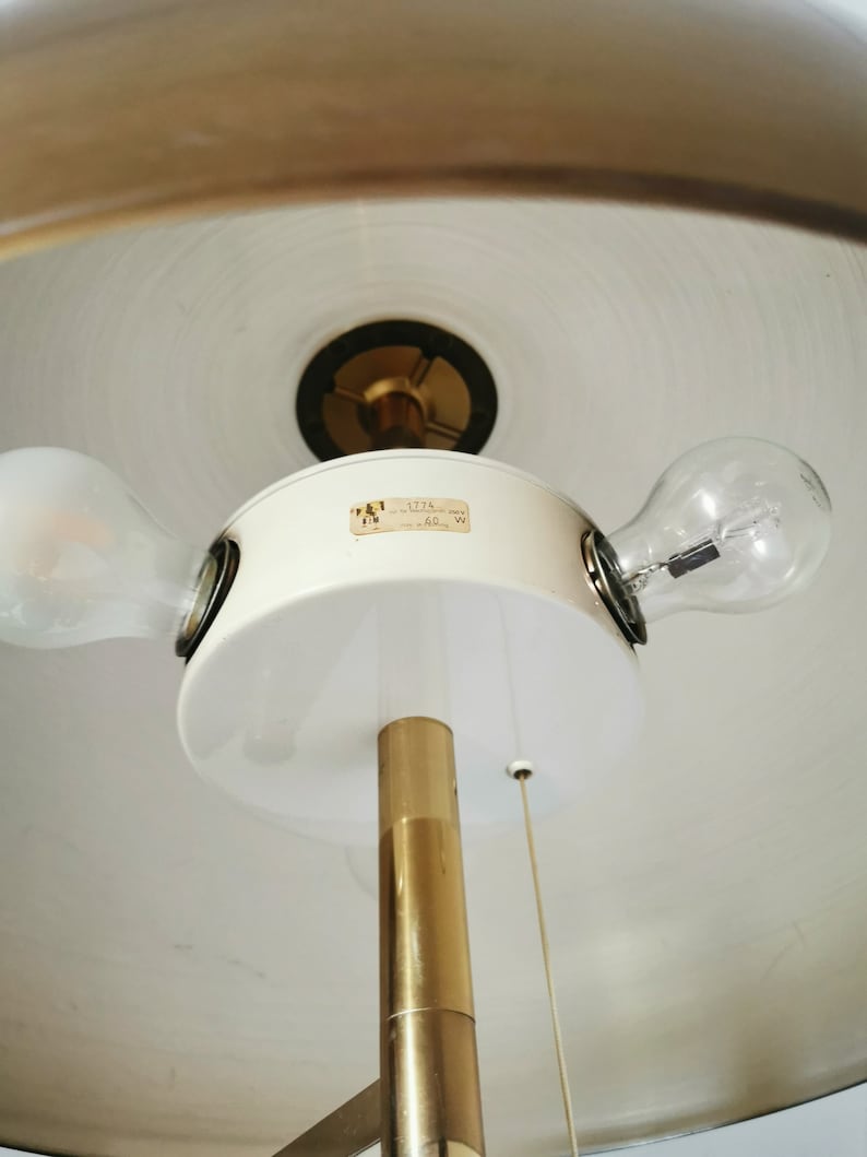 May include: A white and gold floor lamp with two light bulbs. The lamp has a white shade and a gold metal base. The label on the lamp says "127V 60W".