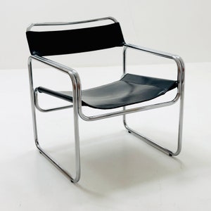 May include: A chrome and black leather chair with a simple, modern design. The chair has a tubular chrome frame and a black leather seat and back.