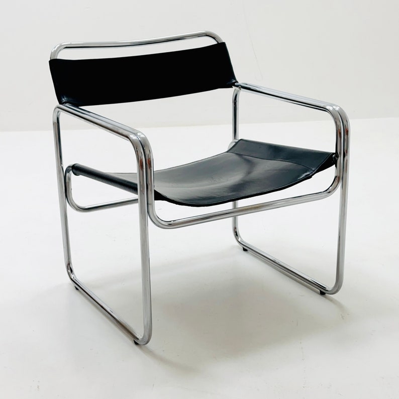 May include: A chrome and black leather chair with a simple, modern design. The chair has a tubular chrome frame and a black leather seat and back.