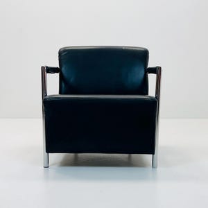 May include: A black leather armchair with chrome legs and arms. The chair has a simple, modern design.