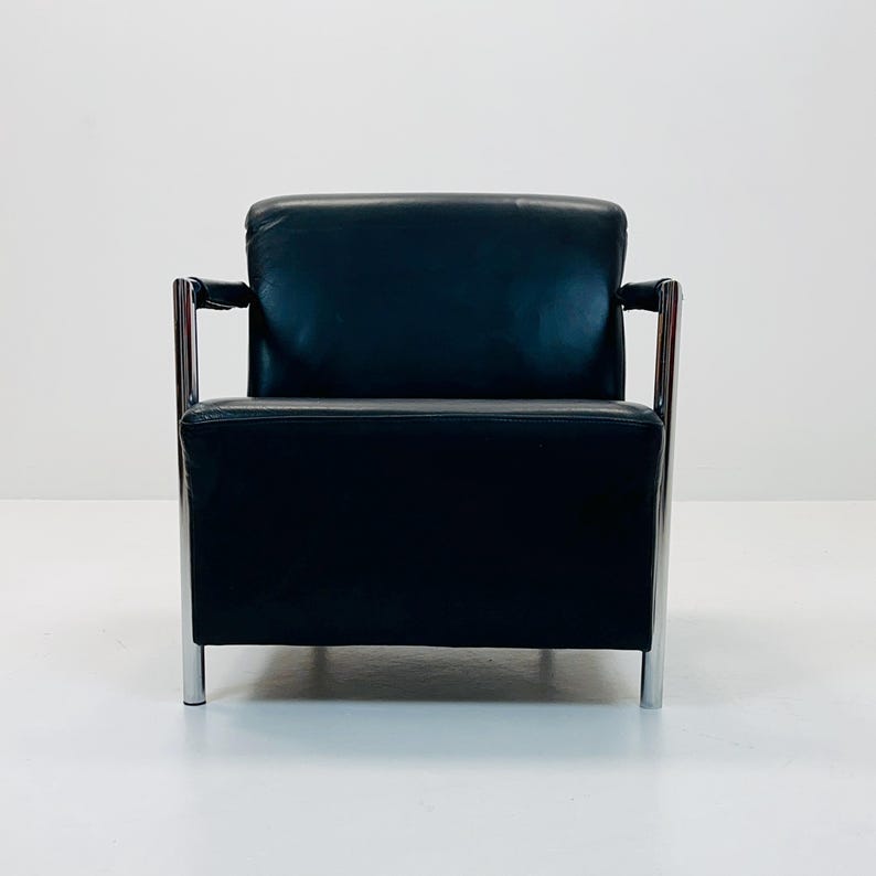 May include: A black leather armchair with chrome legs and arms. The chair has a simple, modern design.