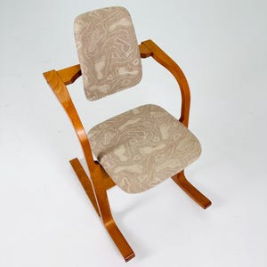Pode incluir: Cadeira vintage com estrutura de madeira curvada e estofamento estampado. O assento e o encosto apresentam um tecido bege com um design abstrato marrom claro. A cadeira tem um design aberto &uacute;nico.
