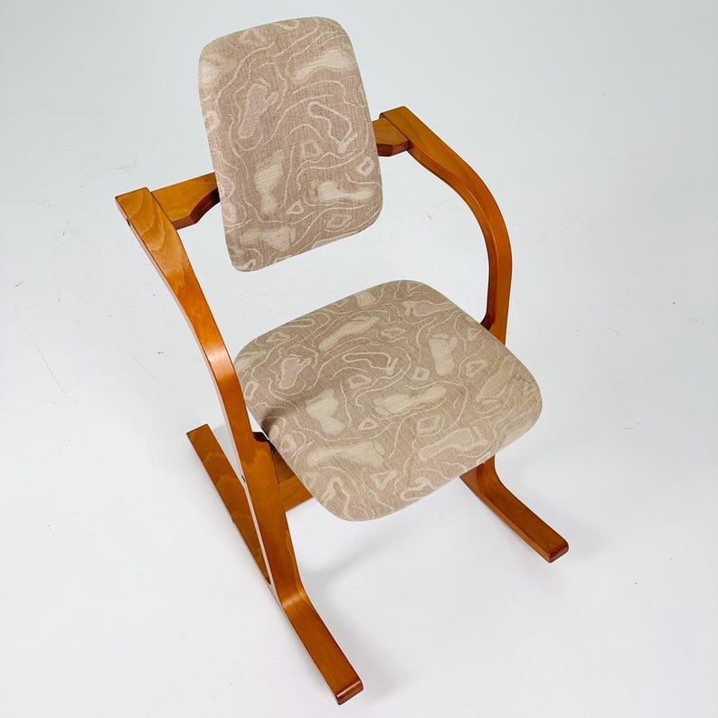 Pode incluir: Cadeira vintage com estrutura de madeira curvada e estofamento estampado. O assento e o encosto apresentam um tecido bege com um design abstrato marrom claro. A cadeira tem um design aberto &uacute;nico.