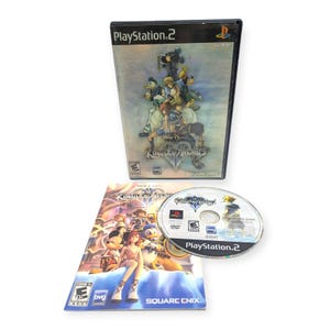 May include: A PlayStation 2 video game case for Kingdom Hearts, featuring a black plastic cover with character artwork, a matching game manual with colorful illustrations, and a circular game disc with the Kingdom Hearts logo and game details.