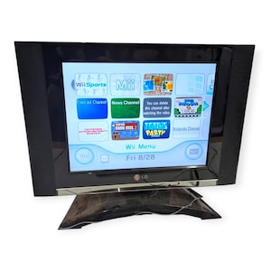 May include: A black LG television displaying the Nintendo Wii menu interface on its screen. The screen shows various channel icons including Wii Sports, Mii, Forecast Channel, News Channel, Super Mario Bros. 2, and Tetris Party, with the date Fri 8/28.