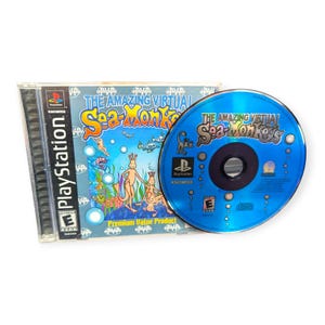 May include: A PlayStation game case and disc for "The Amazing Virtual Sea-Monkeys." The case is clear with a blue and white cover featuring cartoon Sea-Monkeys. The disc is blue with the game title and PlayStation logo.