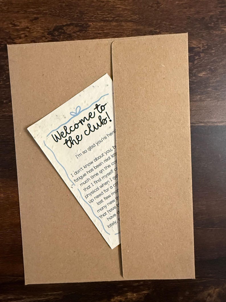 Pu&ograve; includere: Una carta color crema con una superficie ruvida e maculata inserita in una busta di carta kraft marrone. La carta presenta il testo blu scritto a mano Welcome to the club! e I'm so glad you're here, seguito da un paragrafo di testo nero.