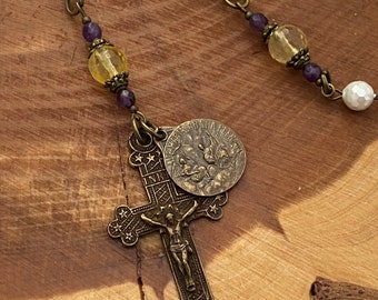 Peut inclure: Un collier de chapelet doré avec des perles de perles blanches, des perles de verre violettes et jaunes, un crucifix et un charme rond en métal avec les mots "MARIA GRATIA PLENA".