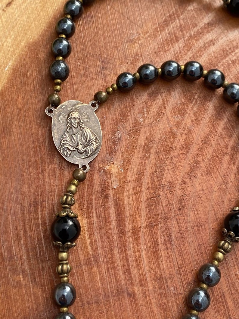 Peut inclure: Un chapelet noir et or avec un pendentif en m&eacute;tal repr&eacute;sentant une image en relief de J&eacute;sus-Christ. Les perles du chapelet sont en onyx noir et en h&eacute;matite.