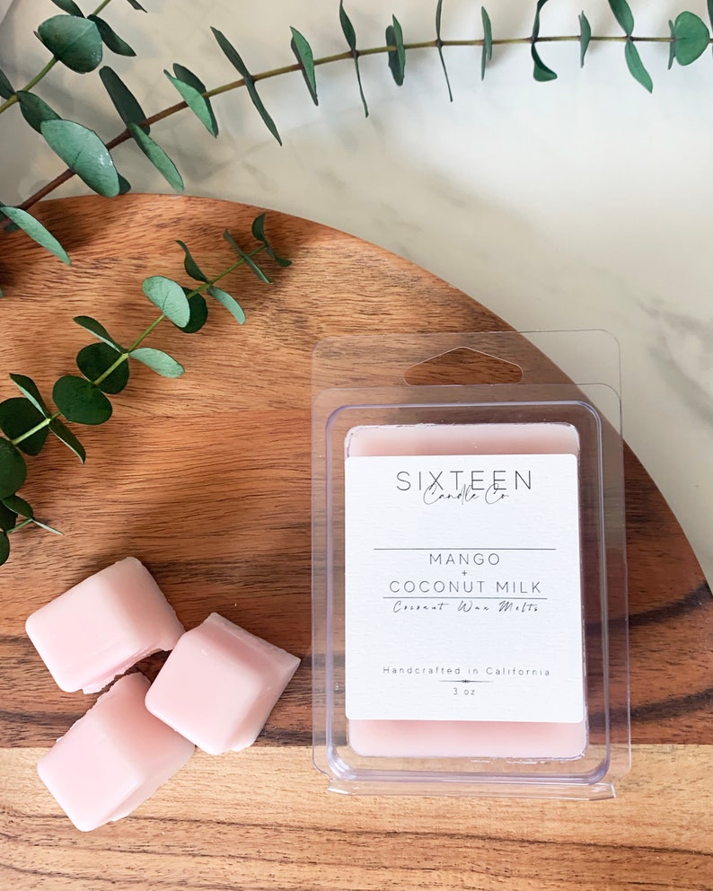 May include: Three pink wax melts in a clear plastic container. The label reads "Sixteen Candle Co. Mango + Coconut Milk Coconut Wax Melts Handcrafted in California 3 oz."