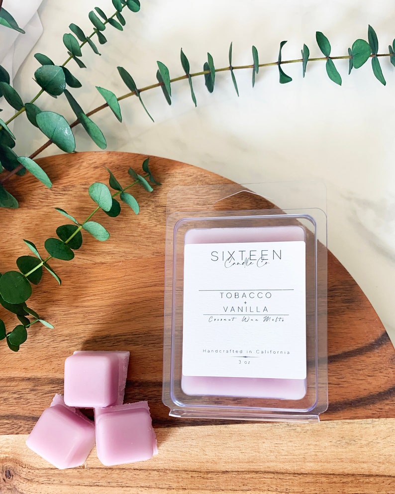 May include: A set of three purple wax melts in a clear plastic container. The label reads "Sixteen Candle Co. Tobacco Vanilla Coconut Wax Melts Handcrafted in California 3 oz."